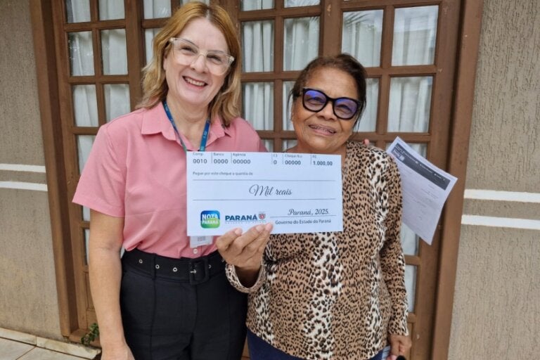 Ganhadora do Nota Paraná segurando o cheque do prêmio.