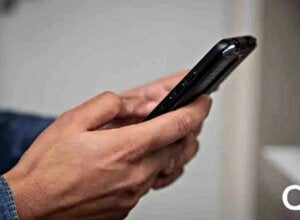 Pessoa segurando celular com ambas as mãos.