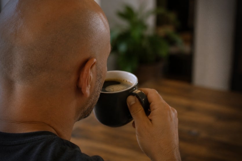 Homem calvo tomando café.
