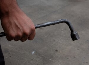 Mão segurando chave de roda.