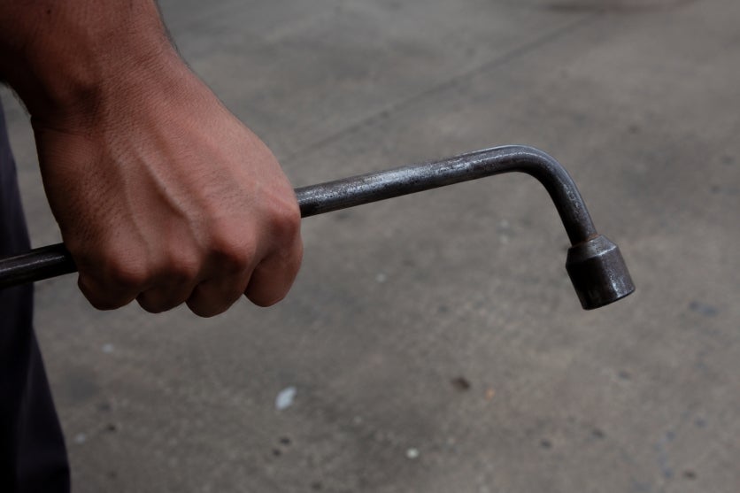 Mão segurando chave de roda.