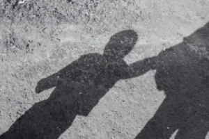 Sombra de criança acompanhada de adulto.