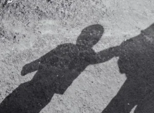 Sombra de criança acompanhada de adulto.