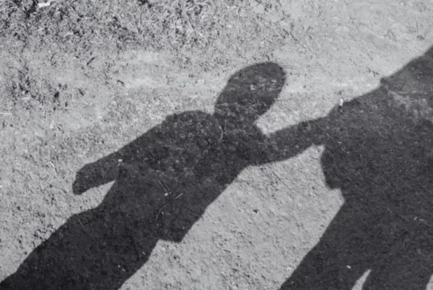 Sombra de criança acompanhada de adulto.