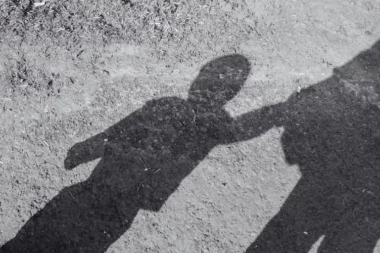 Sombra de criança acompanhada de adulto.