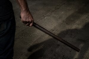 Mão segurando barra de ferro de forma ameaçadora.