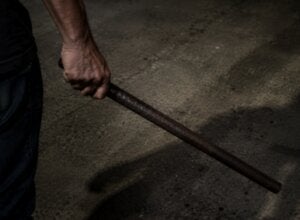 Mão segurando barra de ferro de forma ameaçadora.