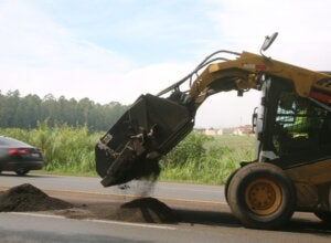 Escavadeira realizando trabalho de reparo em rodovia.
