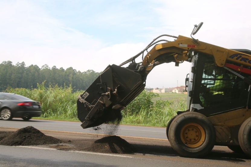 Escavadeira realizando trabalho de reparo em rodovia.
