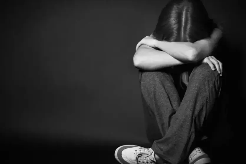 Adolescente abraçando o próprio corpo.