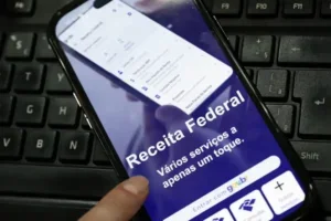 Celular com a tela do menu de acesso da Receita Federal.