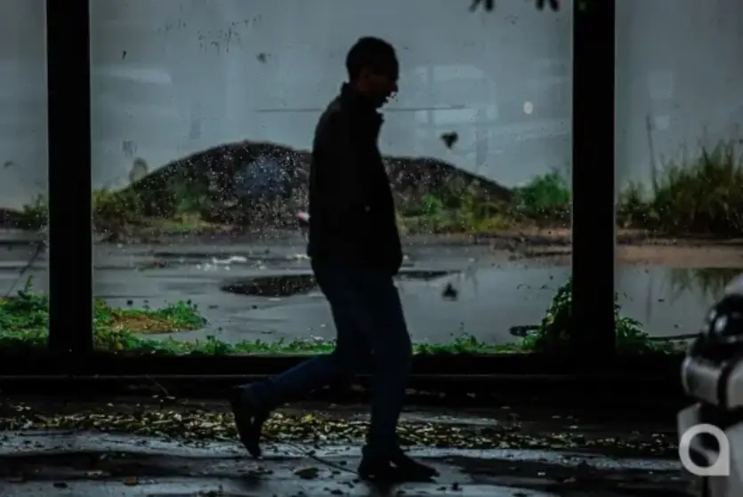 Silhueta de homem andando durante chuva em Umuarama.