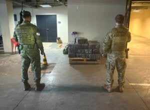 Policiais do BPFron e da PF ao lado de maconha apreendida em porto clandestino de Guaíra.