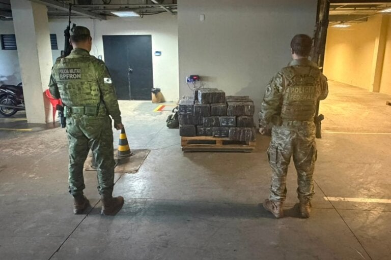 Policiais do BPFron e da PF ao lado de maconha apreendida em porto clandestino de Guaíra.