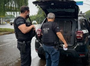 Policiais próximos a um camburão da PCPR.