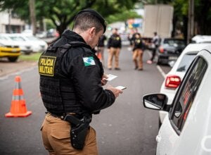 Policial militar verificando documentação de condutor.