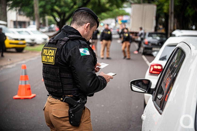 Policial militar verificando documentação de condutor.