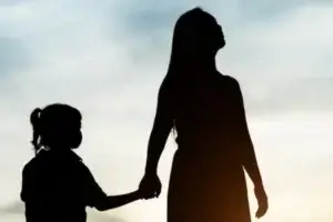 Mãe e filha caminhando de mãos dadas.