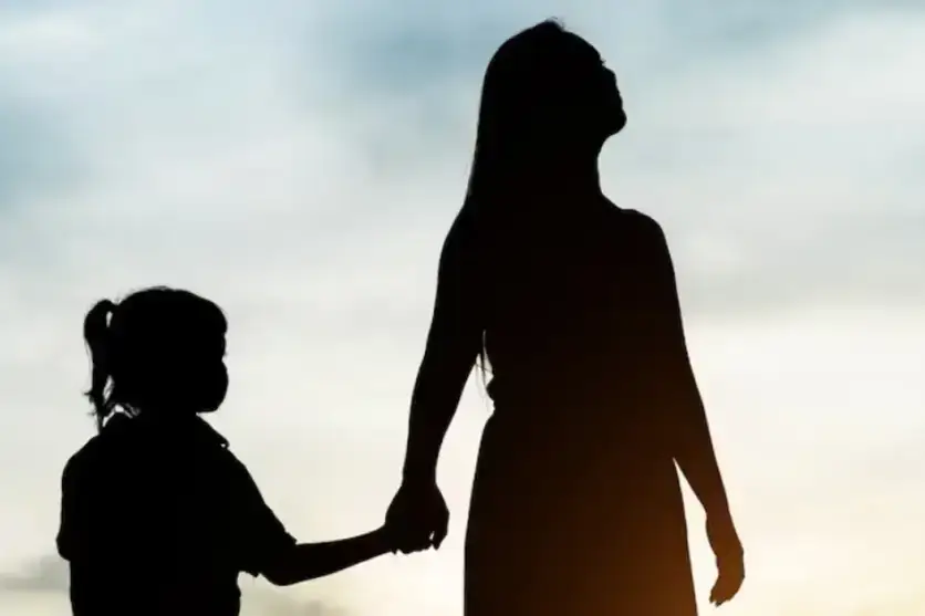 Mãe e filha caminhando de mãos dadas.