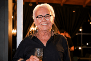 Empresário Benedito Silva, sorridente, com um copo de bebida na mão direita