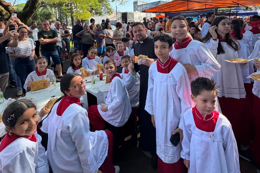 Coroinhas celebram o seu dia fora da igreja, com padre e pastel na feira em Umuarama