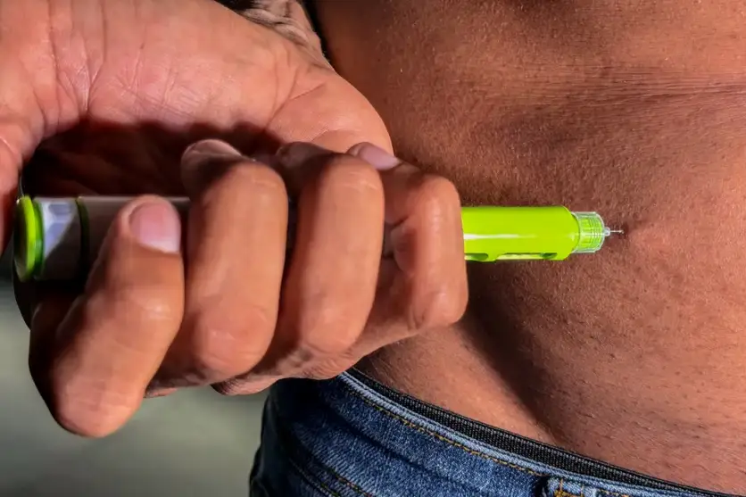 Pessoa aplicando caneta de semaglutida.