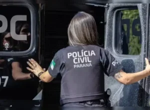 Policial civil acessando o interior de uma viatura da PCPR.