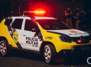 Policial ao lado de viatura da PM.