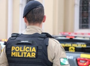 Policial militar próximo a uma viatura.