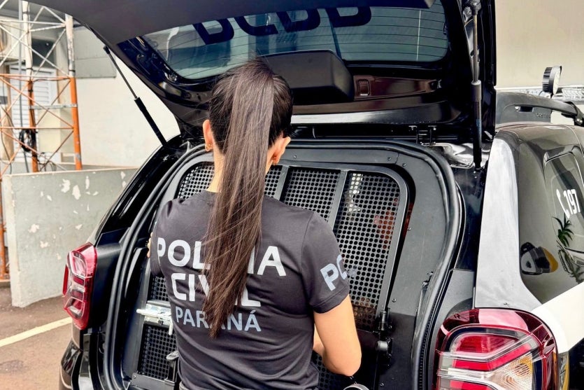 Policial civil ao lado de um camburão da PCPR.