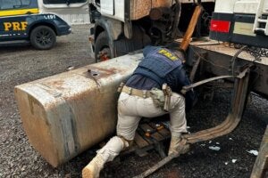 Policial conferindo tanque de carreta com cocaína.