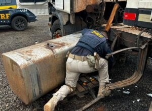 Policial conferindo tanque de carreta com cocaína.