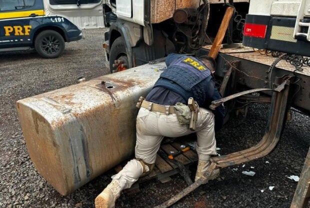 Policial conferindo tanque de carreta com cocaína.