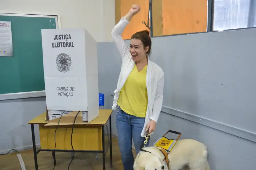 Eleitora cega em cabine de votação.