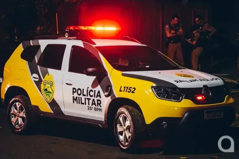 Viatura da PM ao lado de dois policiais.