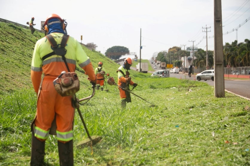 Trabalhadores realizando roçada às margens da PR-323.