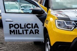 Viatura da PM com a porta do passageiro aberta, revelando o logo da corporação.