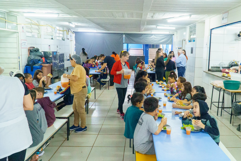 Crianças de escola em Umuarama comendo hambúrgueres durante a Semana da Criança.